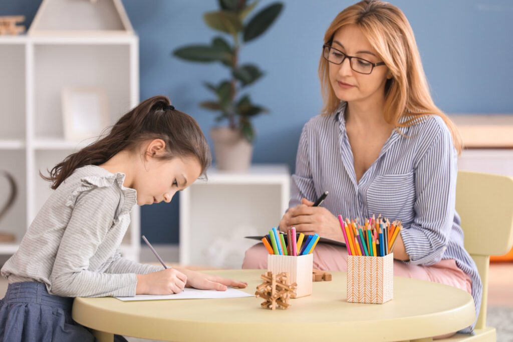 Psychologist working with little girl indoors